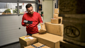 Ein Mitarbeiter im Fulfillment bearbeitet Bestellungen und scannt verschiedene Pakete ein.